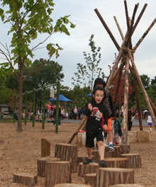 Children play on stepping logs at the Learn + Play Garden at William Hammerschmidt School.