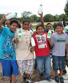 A group of jubilant students, water bottles held high, celebrating water conservation